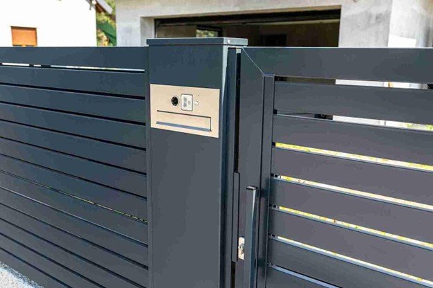 Contemporary metal driveway gate with built-in access controls, installed as part of a professional automatic gate opener service.