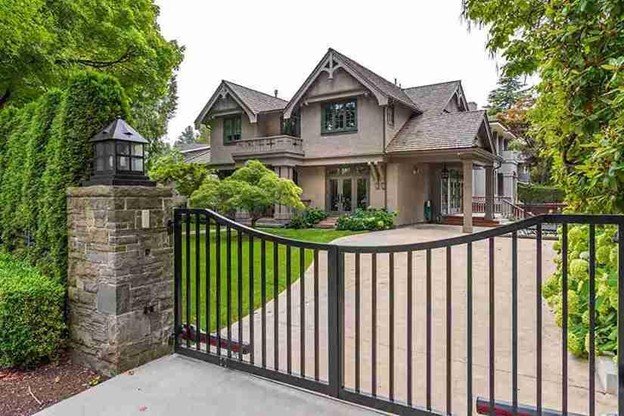 Residential double driveway gate installed in front of a large home, showing symmetrical gate placement and spacing.