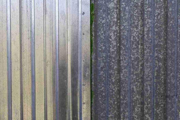Close-up of galvanized metal fence panels attached to sturdy posts, showing secure fasteners and durable construction.