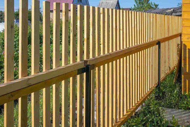 Side-by-side cedar fence with evenly spaced vertical boards along a yard