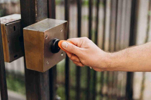 Homeowner using a key fob to activate an automatic gate opener on a secure residential metal gate.