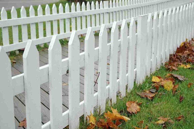 White picket-style fence professionally installed along a residential walkway, showing clean alignment and smooth painted finish