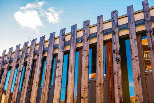 Close-up of a newly installed wooden fence with vertical cedar slats in front of a modern home.