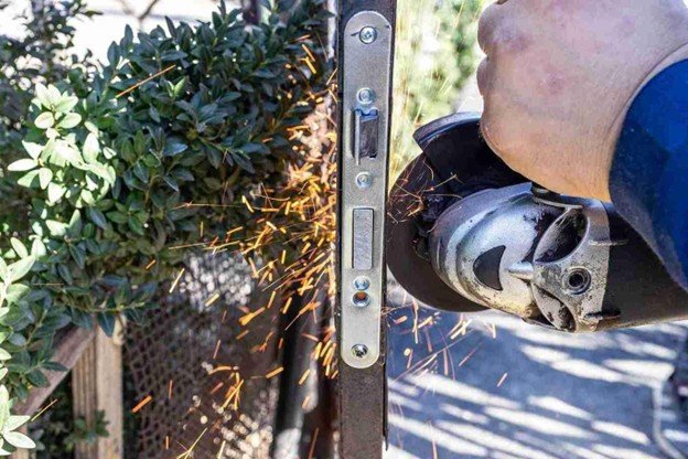 Contractor standing in front of a newly installed wooden gate holding tools