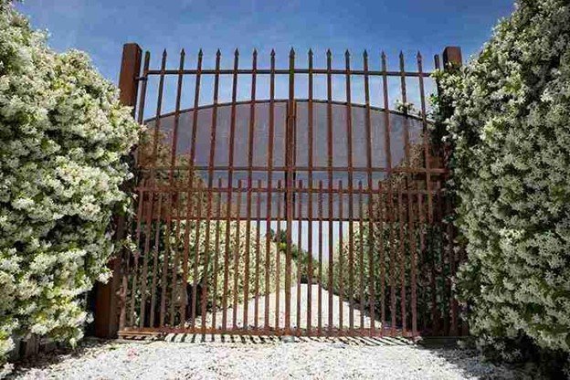 Tall metal double gate installed between hedges, showing secure design and professional installation quality.